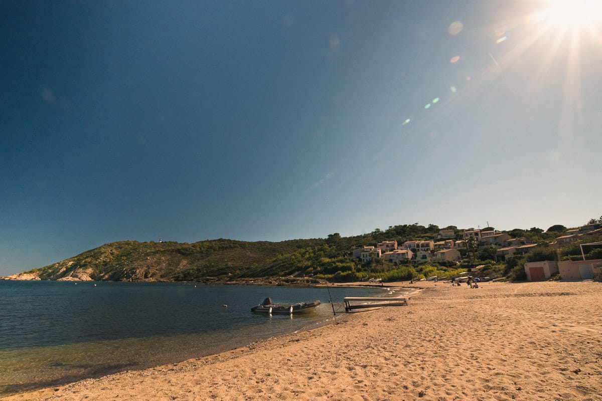 Plage ensoleillée de Bonne Terrasse avec sable doré, mer calme et collines en arrière-plan.