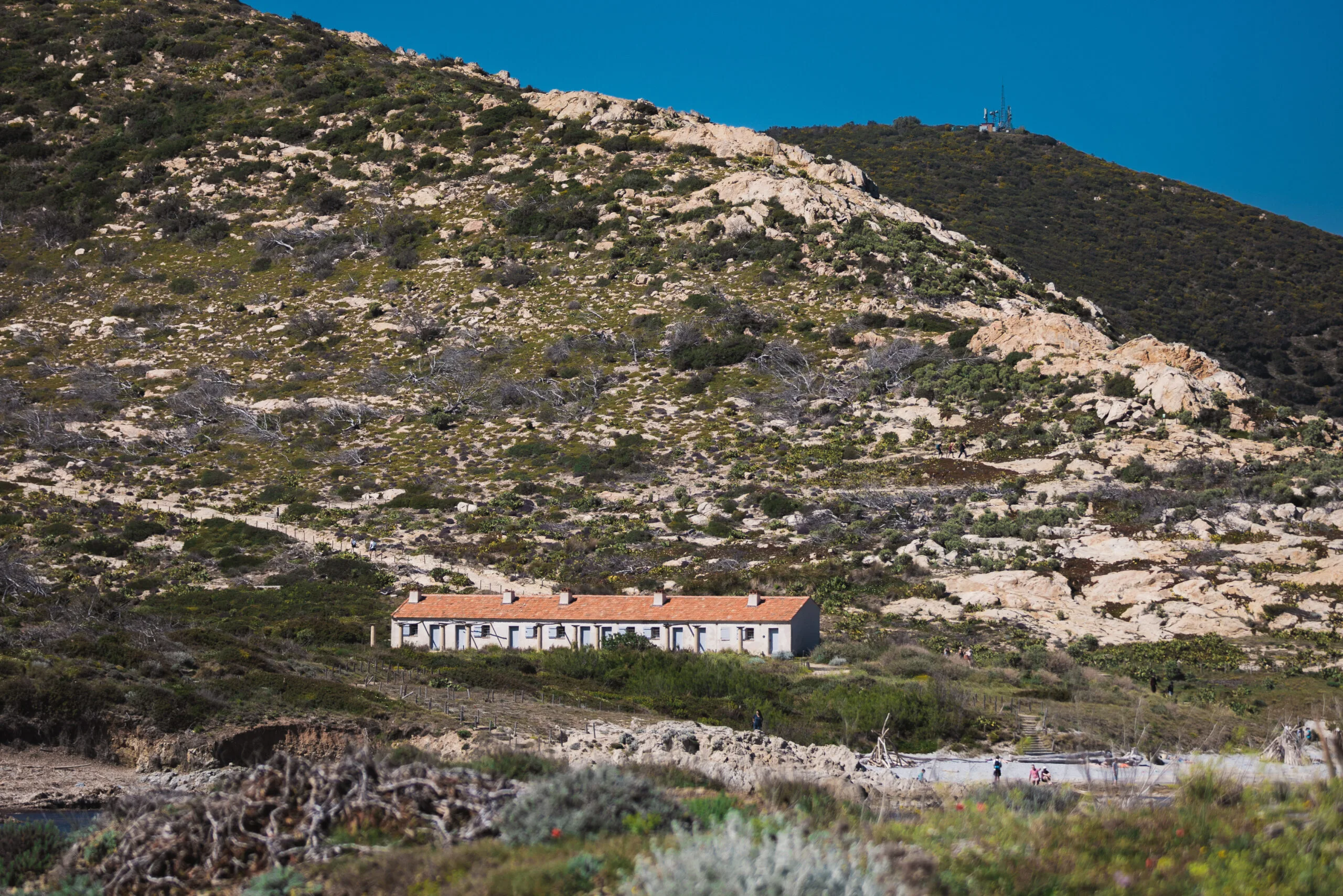 Bâtiment aux toits rouges au pied des collines rocheuses du Cap Taillat